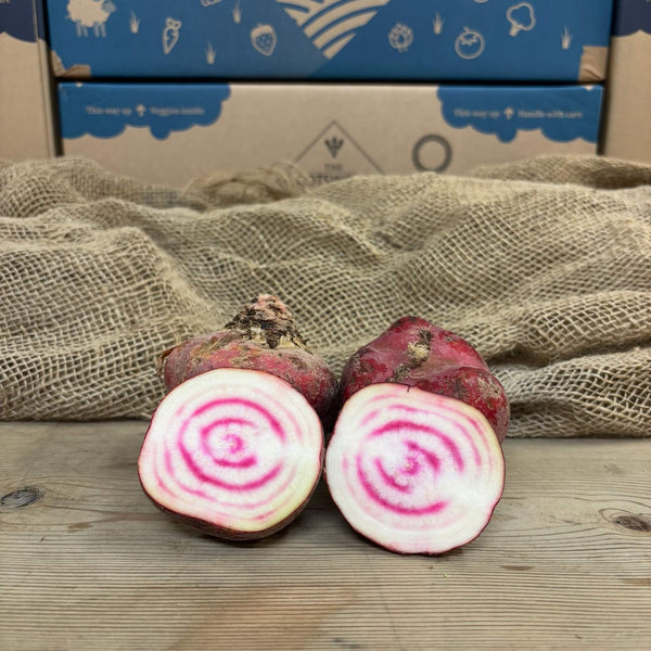 Two halves of a candy beetroot split revealing vibrant pink and white concentric rings. 