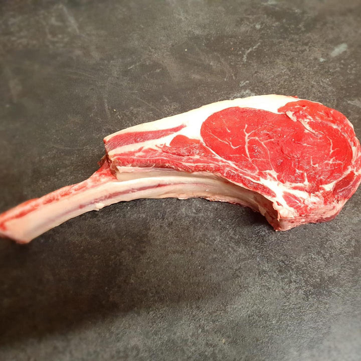 A raw David Moore’s Tomahawk Steak with a long rib bone. 