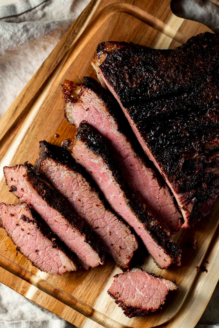 A succulent roasted David Moore’s Beef Brisket, sliced on a wooden cutting board.