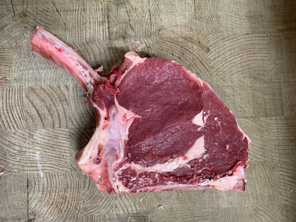 A raw David Moore's cote de boeuf steak with a thick cut of beef and an exposed rib bone