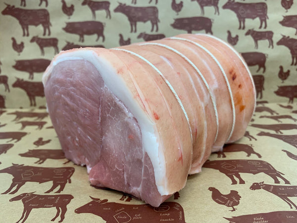 A fresh free-range pork shoulder joint with a layer of scored fat, neatly tied with string.