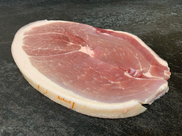 A thick cut of raw David Moores gammon steak with a layer of fat around the edge.