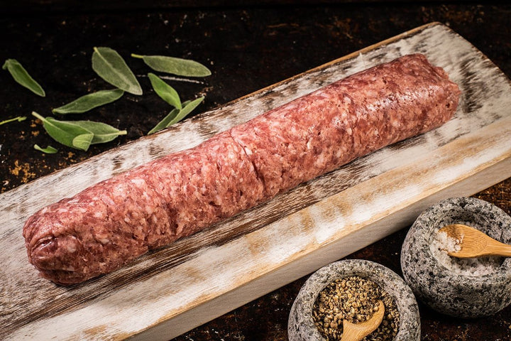 Unwrapped sausage meat log placed on a rustic wooden board.